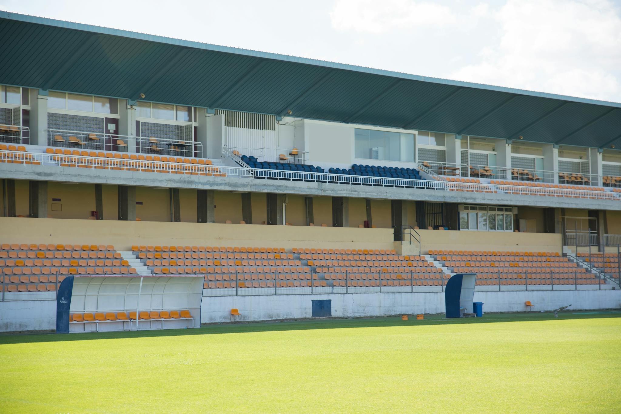 A wide-angle view of an empty sports stadium with bleachers and orange seats, suitable for various sports.