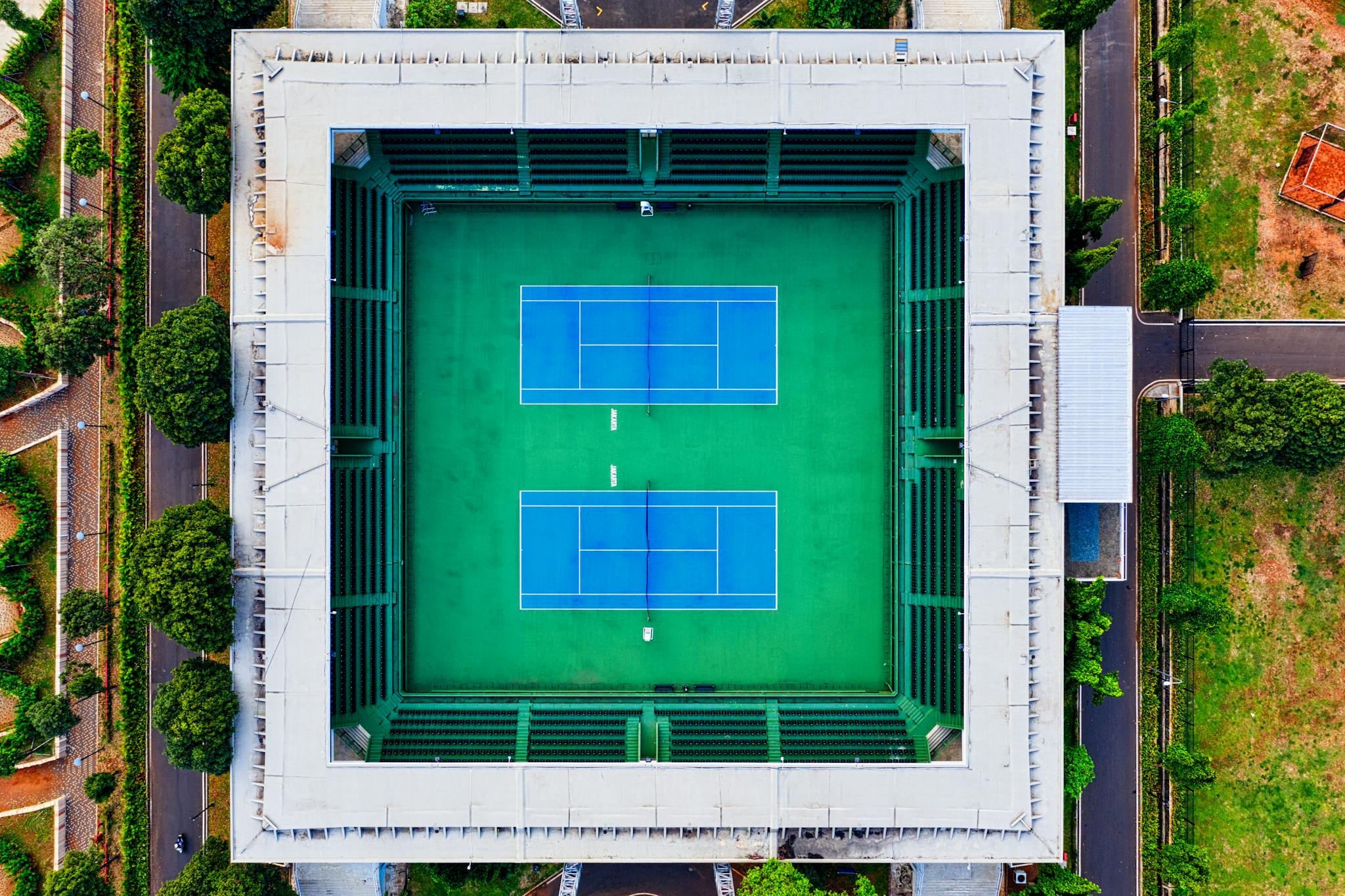 Aerial shot of an empty tennis stadium in Jakarta, showcasing modern design and vibrant green courts.